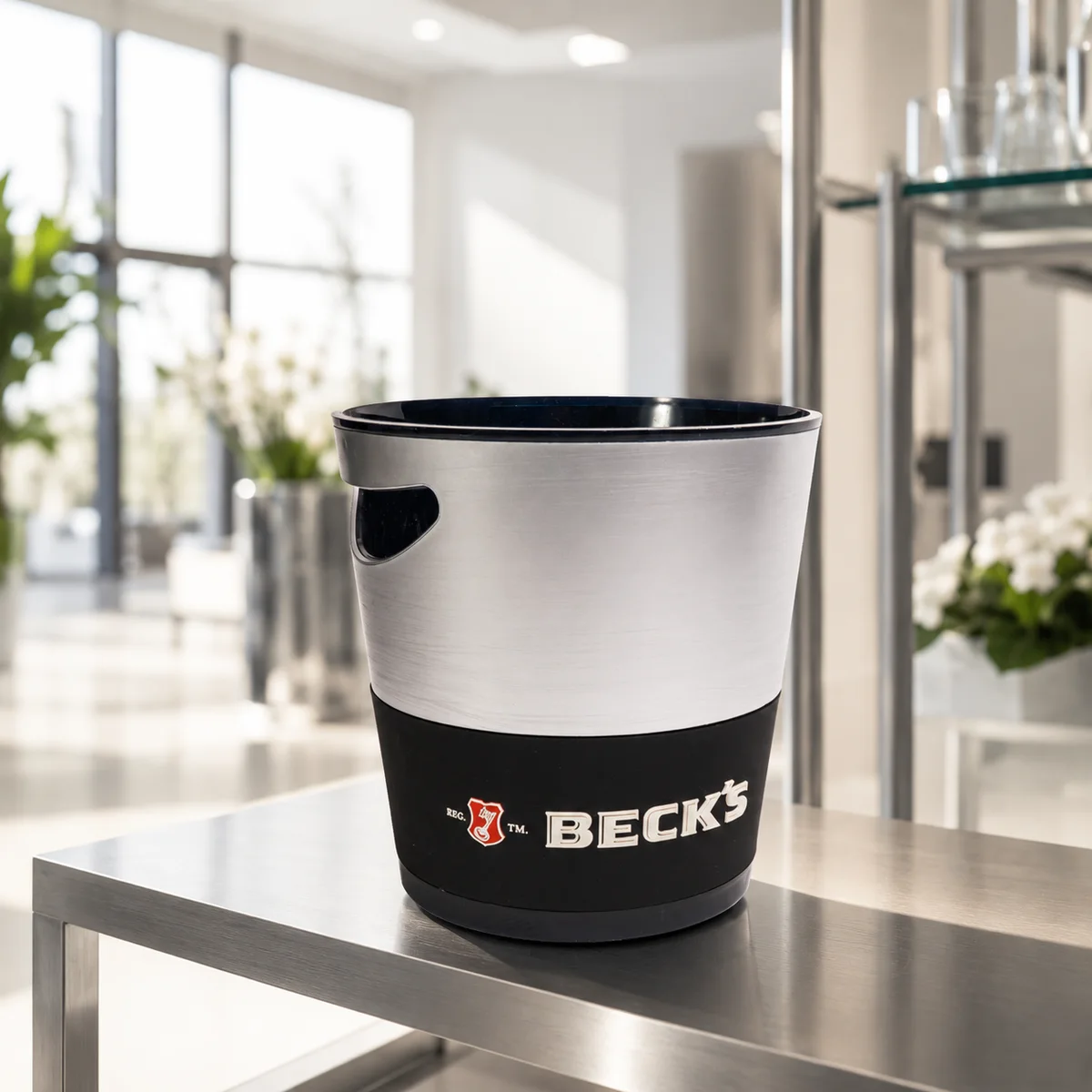 Kétszínű, acél és fekete jégvödör Beck's emblémával, világos éttermi asztalon