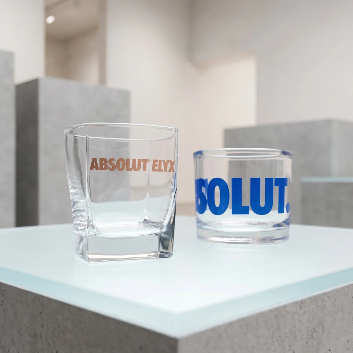 Két üvegedény – gravírozott Absolut Elyx és kék nyomott Absolut felirat –, világos teraszon