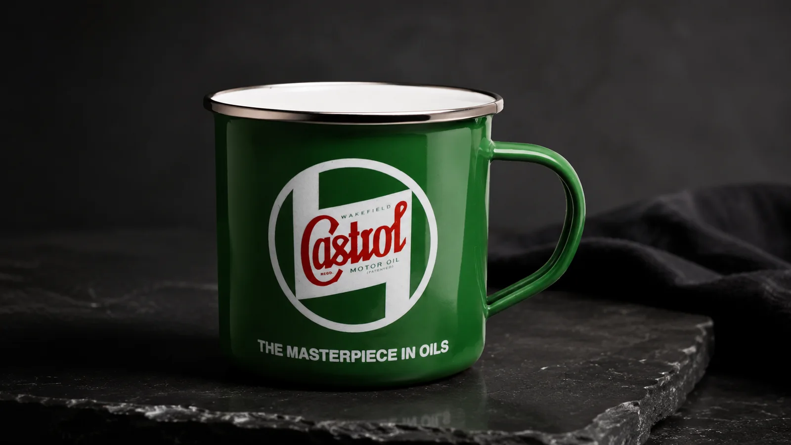 Zöld zománcozott Castrol bögre sötét háttér előtt, palatálcán