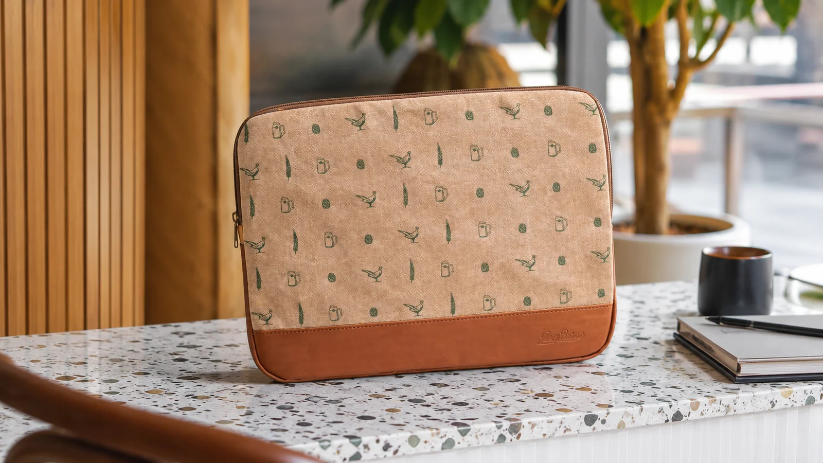 Homokszínű laptoptok apró mintával és bőr díszítéssel, világos márványpulton
